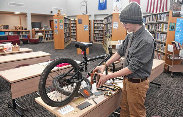 Student Maximus Parsons shows where he will mount the electric motor onto a BMX bike conversion.